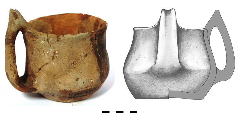 Kubek typu K21a, niezdobiony. Krawędź zaokrąglona, dno niewyodrębnione,  ucho taśmowate typu ansa lunata. Domieszka tłuczonego kamienia i krzemienia. H – 10 cm (bez ucha), 13,3  cm (z uchem), R1 – 10,8  cm, R2 – 10,5 cm, R3 – 13,5  cm, R4 – 9,5 cm
