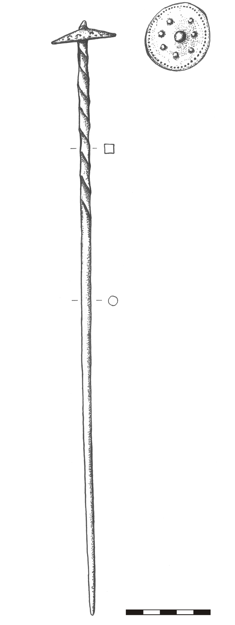 Szpila brązowa z główką gwoździowatą (kapeluszowatą), tordowaną w górnej części nóżki. Drut w przekroju kolisty, u góry – kwadratowy, o grubości 0,4 – 0,6 cm. Długość nóżki – 36,5 cm; główka owalna w planie, o wymiarach 4,3 × 4 cm, zdobiona dookolnie na obwodzie małymi wypustkami, w centrum – wiekszą wypustka otoczona dookolnie przez siedem mniejszych